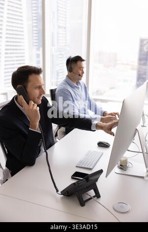 Busy diverse client support operators managing customer calls by computers Stock Photo