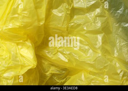 Crumpled yellow plastic surface with irregular folds and creases creating a bright abstract texture Stock Photo