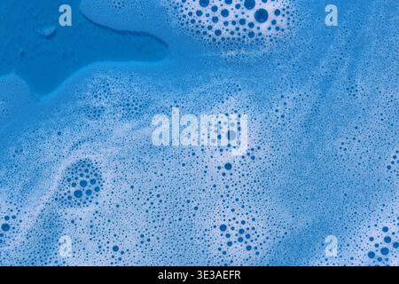 Close-up of blue soapy water with bubbles creating a swirling textured pattern background Stock Photo