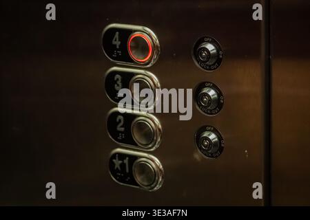 A close-up view of a stainless steel elevator control panel with buttons for floors 1 through 4, the 4th floor button is illuminated in red Stock Photo