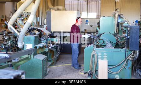 Carpenter operating machinery in wood factory workshop Stock Photo