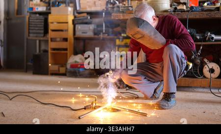 Senior artisan welding metal in a workshop Stock Photo
