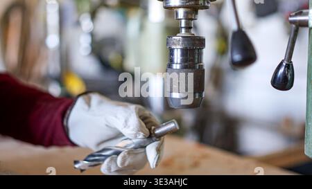 Person changing drill bit on a machine press in workshop Stock Photo