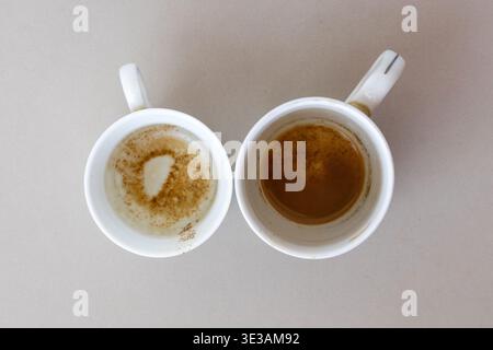 Top view of two empty white ceramic tea cups with leftover tea stains on the bottom after finishing a morning drink. Perfect for depicting the end of Stock Photo