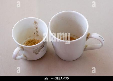 Close-up of a pair of used white mugs with remaining tea or coffee particles inside after finishing refreshment. Excellent for cafe marketing, morning Stock Photo