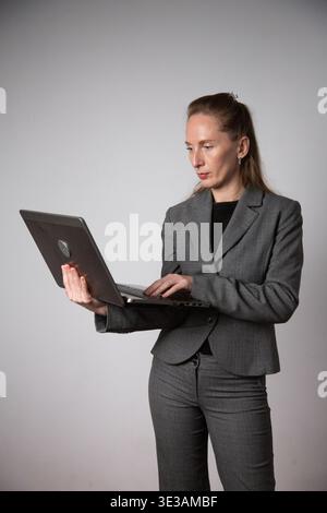Vertical photo. A woman in a business suit holding a laptop Stock Photo