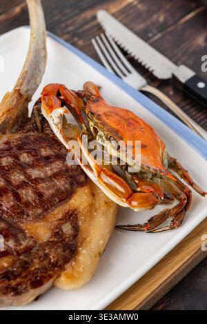 Grilled tomahawk steak with lobster tail served on wooden board Stock Photo