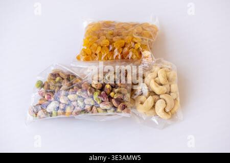 Close-up of peeled pistachio kernels, golden raisins, and cashew nuts packed in clear polythene packets for retail. Perfect for depicting nut industry Stock Photo