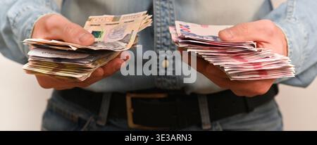 person holding large stacks of cash in hands, showing several bundles of money. hand with money. man with bundles of cash. human with pack of Ukrainia Stock Photo