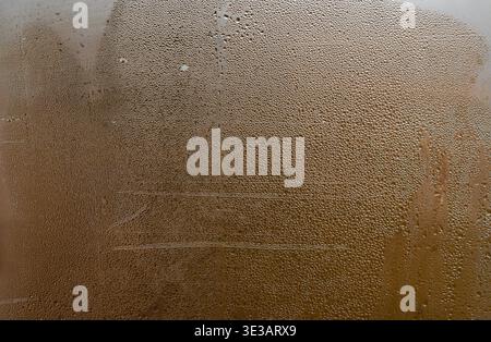 Moist glass surface covered with condensation droplets, abstract pattern of water forming texture, blurred natural light creating modern and soft back Stock Photo