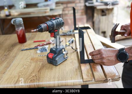 Focused craftsman at woodworking and carpentry. handyman using hammer tool on wood furniture in diy workshop. Concentrated on craft of building Stock Photo