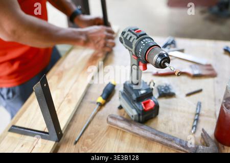 Focused craftsman at work in workshop, woodworking with drill and tool. carpenter busy with DIY project, build and repair job using wood and equipment Stock Photo