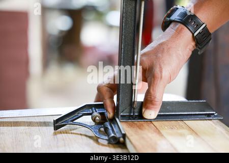 Close up of carpenter hand working with precision and skill. Using square tool to measure wood plank for project, demonstrating focused concentration Stock Photo