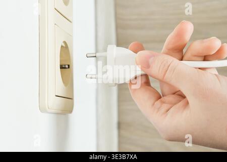 Hand holding electrical plug ready for power connection. Stock Photo