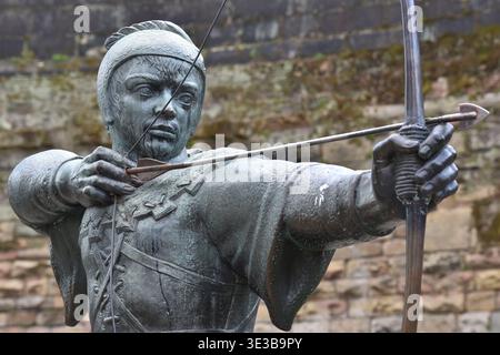The Robin Hood statue stands proudly on Castle Road in Nottingham, England, aiming his arrow toward the historic gatehouse of Nottingham Castle. Stock Photo