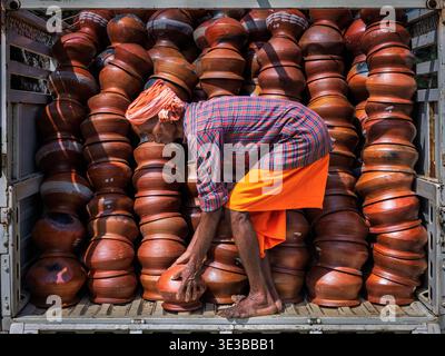 Elderly man working in the back of a lorry full of clay bowls, Odisha, India Stock Photo