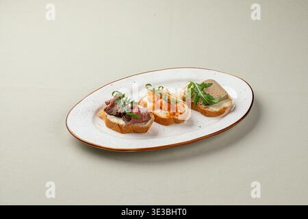 Assorted bruschetta with toppings on white plate Stock Photo