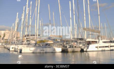 Softly blurred view of sailing yachts in a sunny marina, creating an abstract nautical background.  Stock Photo