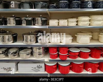 Assortment of colorful cooking pots and stainless steel kitchenware displayed on shelves in a retail department store. Stock Photo