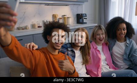 Multiethnic friends men women taking selfie video at home funny faces grimacing diverse group couch African American Caucasian girls guys buddies Stock Photo
