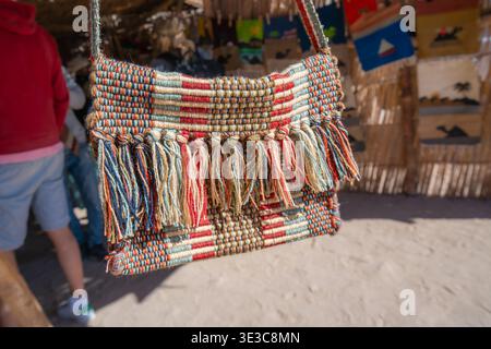 HURGHADA, EGYPT - JANUARY 19, 2025: A colorful handmade woven bag with tassels displayed at a traditional Bedouin village market in Hurghada, Egypt. Stock Photo