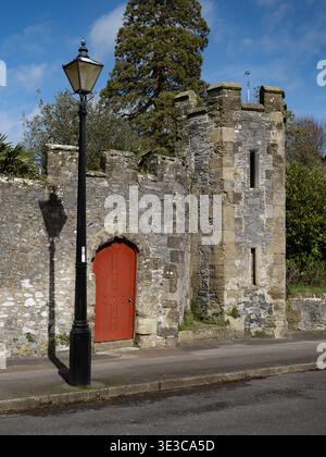 The Medieval castle walls in Arundel away from the main castle surrounding the gardens called the Stumpery with its impressive red gate and tower Stock Photo