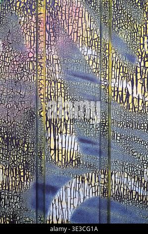 Abstract cracked paint texture with purple and yellow hues and spray paint details Stock Photo