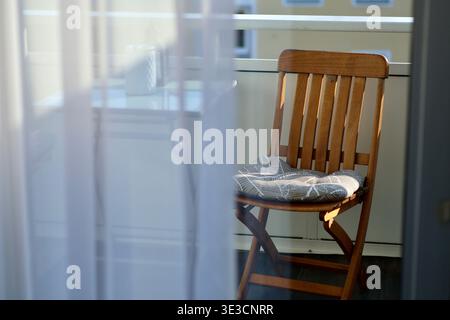 Empty folding chair in front of white wooden fence in sunny backyard. Stock Photo