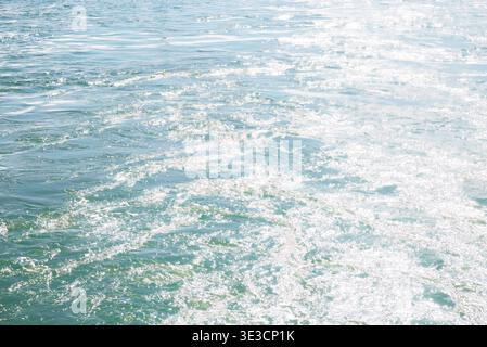 Auckland, New Zealand: Sunlight reflects off blue Waitemata Harbour sea water surface during ferry boat transit to Devonport. Stock Photo