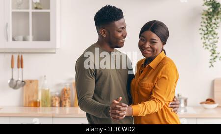 Young Happy Black Spouses Dancing Together In Kitchen, Having Fun At Home Stock Photo