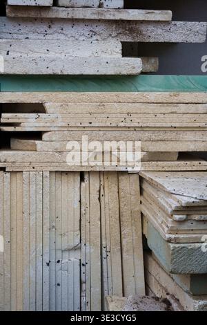Stack of various building insulation boards and foam panels in shades of beige and green, showing different textures and layered arrangement Stock Photo