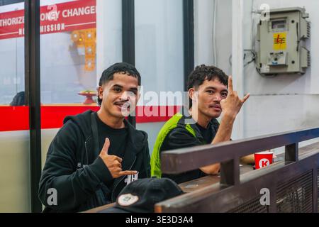 Two Young Men Making Hand Gestures Behind a Counter Stock Photo