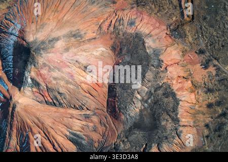 Striking aerial perspective of a massive abandoned slagheap, showing deep erosion gullies and colorful layers of mineral oxidation and coal. This eerie industrial landscape with no people looks like a sci-fi alien world, a powerful image of environmental impact. Stock Photo
