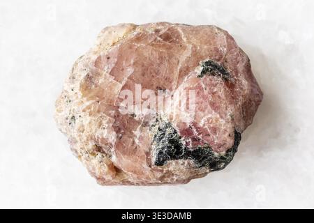 Close-up sample of raw pink ruby mineral on white marble background Stock Photo