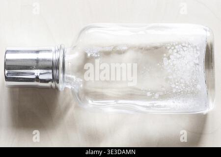 Lying empty glass bottle with white spots from the glass disease on a wooden table Stock Photo