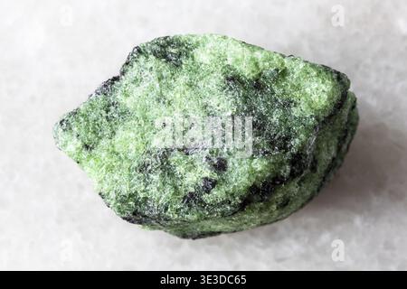 Close-up sample of raw zoisite rock on white marble background Stock Photo