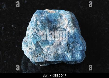 Close-up view of rough blue apatite rock on black granite background Stock Photo