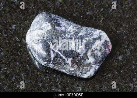 Close-up sample of polished antimonite rock on black granite background from Kyrgyzstan Stock Photo