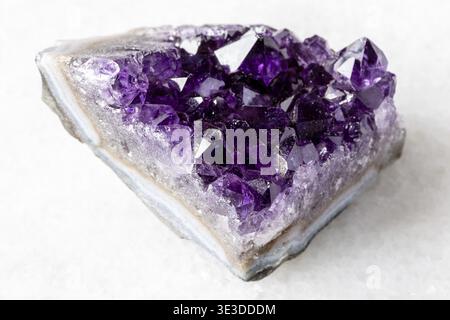 Sample of a rough geode made of amethyst mineral crystals on a white marble background, close-up from Russia Stock Photo