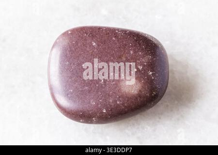Sample of polished reddish brown quartzite rock on white marble background, close-up from Karelia, Russia Stock Photo