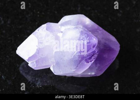 Close-up sample of rough amethyst crystals on black granite background from Madagascar Stock Photo