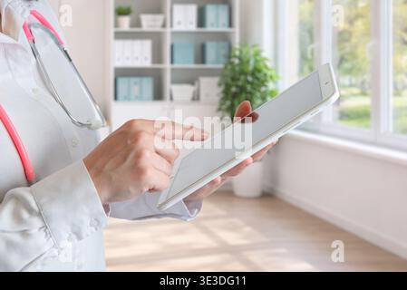 doctor using tablet in clinic near window representing digital healthcare, medical applications and telemedicine services Stock Photo