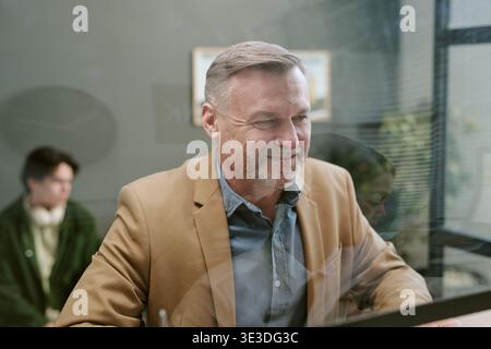 Middle Aged Caucasian Man Smiling While Working at Bank Branch Desk Stock Photo