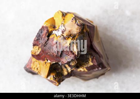 Close-up sample of raw colorful mookaite rock on white marble background Stock Photo