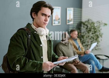 Portrait of Young Caucasian Man Holding Documents Waiting in Bank Branch Stock Photo