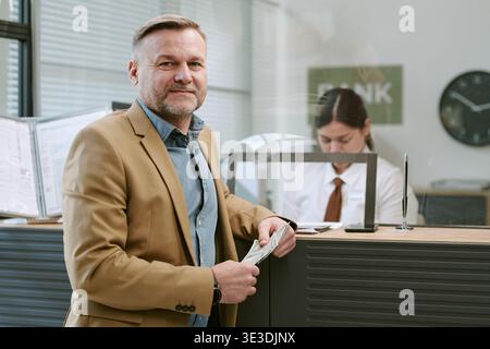Portrait of Middle Aged Caucasian Man Holding Cash Standing in Bank Branch Stock Photo