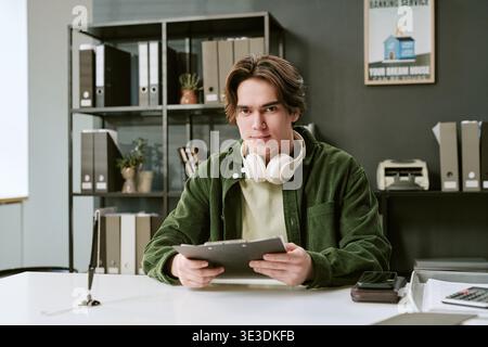 Portrait of Caucasian Young Adult Man Using Digital Tablet at Bank Branch Stock Photo