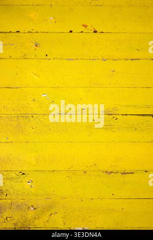 Bright yellow wooden surface with weathered texture and horizontal planks. Small scratches and paint chips add rustic charm. Perfect for backgrounds, Stock Photo