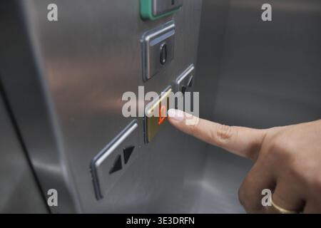 Hand presses elevator button in a building hallway Stock Photo