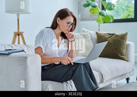 Middle aged serious woman working with laptop Stock Photo